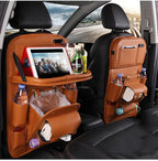 Car seat back organizer in brown leather with tablet holder, cup holders, tissue box, and storage compartments