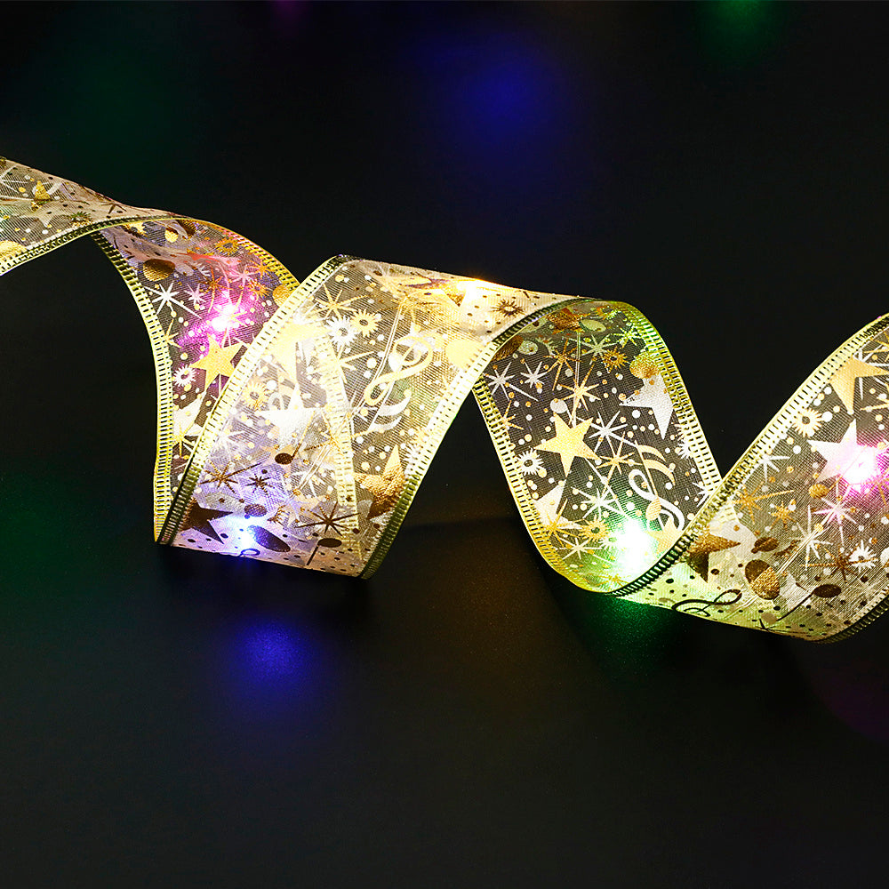 Gold decorative ribbon with star and musical note patterns illuminated by colorful LED lights on black background