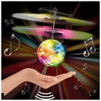 Hand holding colorful glowing disco ball helicopter with spinning blades and musical notes