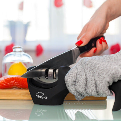 Person sharpening a knife with Kyvit knife sharpener in bright kitchen with salmon and lemon in the background