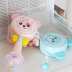 Pink and blue bear-themed baby rattles with yellow bow and textured handles on white surface
