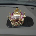Decorative gold crown with red gems and purple gemstone on car dashboard