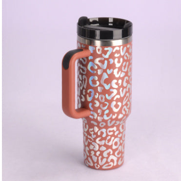 Insulated travel mug with orange and white leopard print design and black lid on light purple background