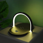 Modern black LED desk lamp with curved light and wireless charging pad on white table