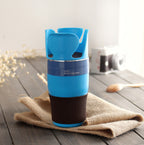 blue auto mug cup with black base on wooden table with beige cloth and blurred camera in background