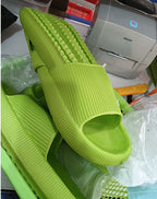 Bright green textured slide sandals resting on plastic and fabric materials with a printer in the background