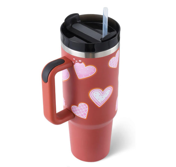 red travel tumbler with hearts design, black lid, and straw, insulated coffee cup