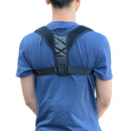Person wearing black posture corrector brace over blue t-shirt, back view isolated on white