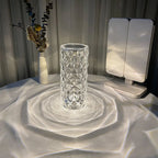 Clear geometric crystal vase creating light patterns on white table with dried flower arrangement and white device
