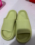 Pair of light green rubber slide sandals with textured straps on white surface