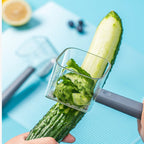 Hand using a gray vegetable peeler to peel a long cucumber over a blue surface with sliced cucumber inside the peeler