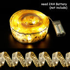 Battery-operated golden star fairy lights ribbon with 2AA battery pack on black background